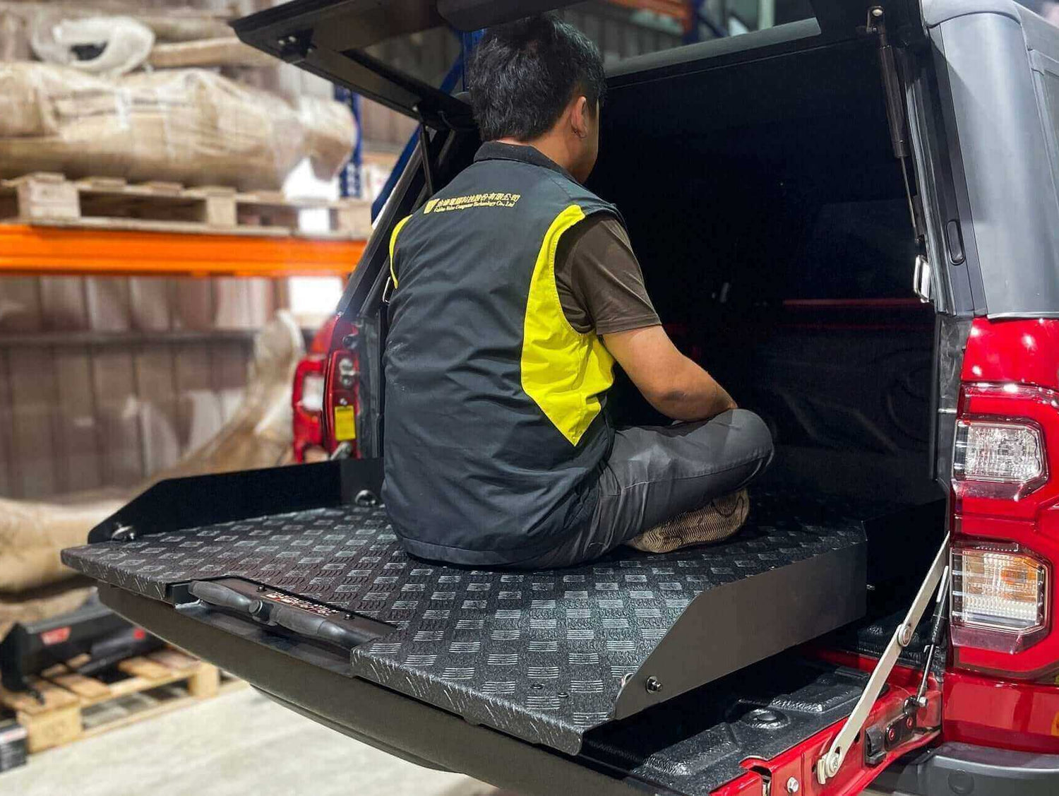 Person using ute slide tray in Toyota Hilux, showcasing UniUte Sliding Tray Drawer for models 2004-2025.