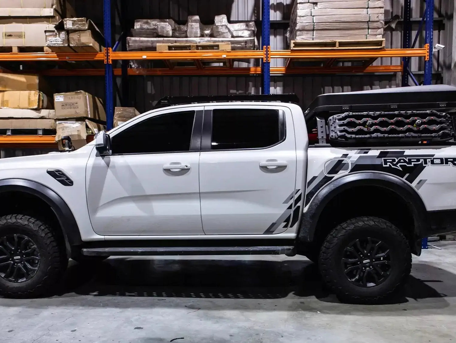 White pickup truck with tub rack carrying gear in a warehouse
