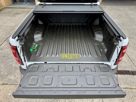 Open truck bed showing BYD Shark 6 tub cover with quad-fold hard lid installed on 2025+ model.