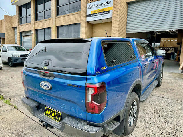ford ranger canopy on blue NextGen RA 2022-2025 truck parked outside a building, showcasing UniUte FORCE PRO design