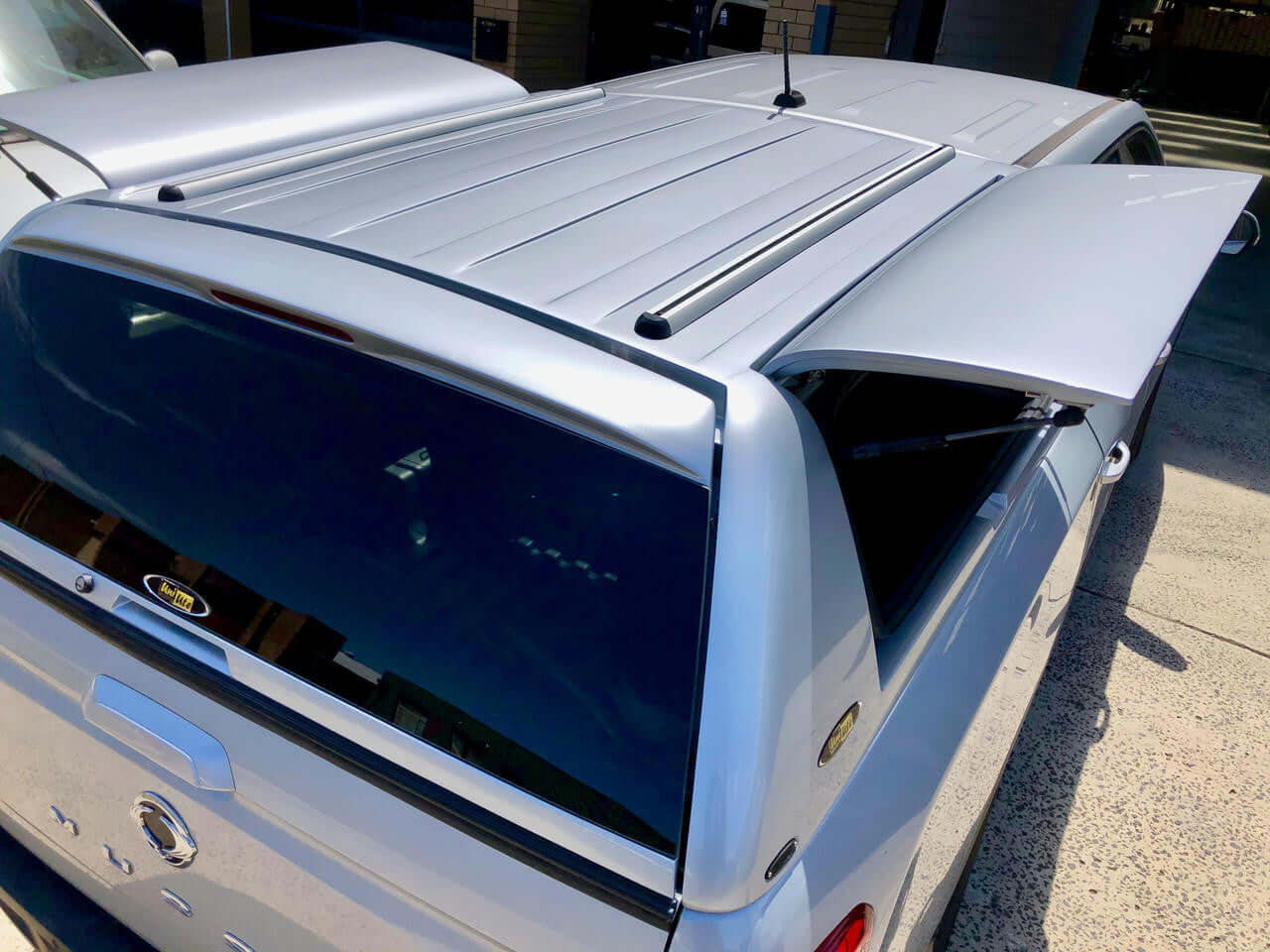 SsangYong Musso XLV Canopy installed on a silver pickup truck, showcasing roof design and rear window detail.