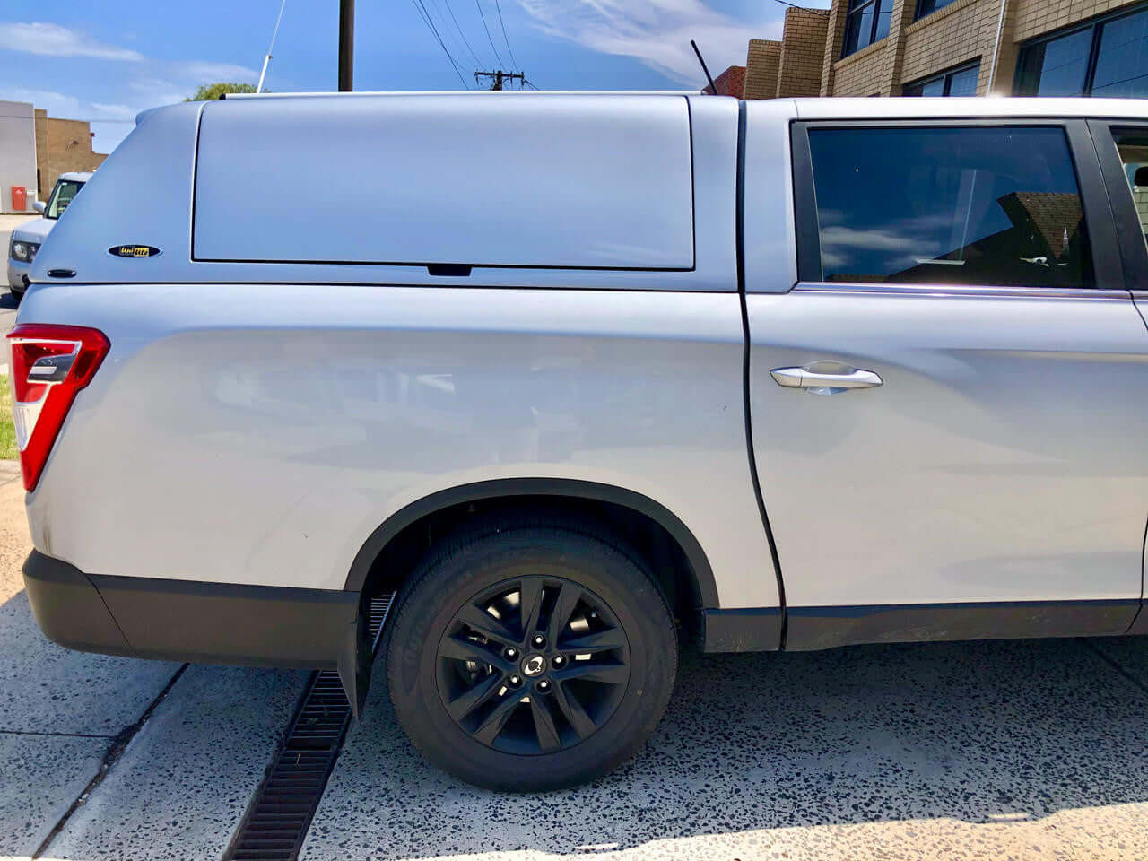 SsangYong Musso XLV Canopy installed on a silver long tub truck parked outside