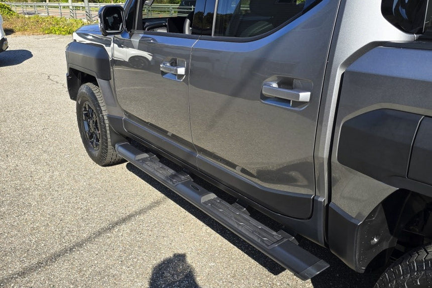 KIA Tasman side steps 2025+ black side bars for enhanced access and style on a premium KIA vehicle, shown in outdoor setting.