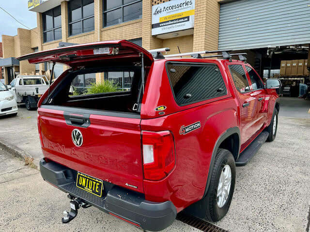 Red Volkswagen Amarok canopy by UniUte, open, 2023 model parked outside warehouse, focus keyword: amarok canopy